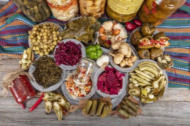 Ev yapımı turşu sergisi. Turşu kavanozu tipleri. Tahta masada farklı türde meyve ve sebze turşusu. Salatalık turşusu, domates, lahana, biber ve sarımsak, salatalık turşusu..