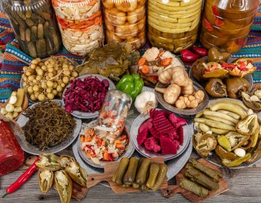 Ev yapımı turşu sergisi. Turşu kavanozu tipleri. Tahta masada farklı türde meyve ve sebze turşusu. Salatalık turşusu, domates, lahana, biber ve sarımsak, salatalık turşusu..