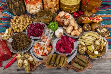 Ev yapımı turşu sergisi. Turşu kavanozu tipleri. Tahta masada farklı türde meyve ve sebze turşusu. Salatalık turşusu, domates, lahana, biber ve sarımsak, salatalık turşusu..