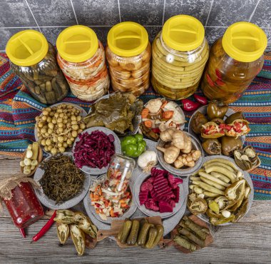 Ev yapımı turşu sergisi. Turşu kavanozu tipleri. Tahta masada farklı türde meyve ve sebze turşusu. Salatalık turşusu, domates, lahana, biber ve sarımsak, salatalık turşusu..