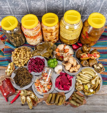 Ev yapımı turşu sergisi. Turşu kavanozu tipleri. Tahta masada farklı türde meyve ve sebze turşusu. Salatalık turşusu, domates, lahana, biber ve sarımsak, salatalık turşusu..