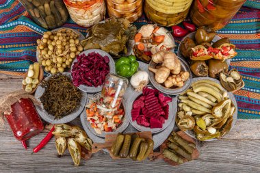 Ev yapımı turşu sergisi. Turşu kavanozu tipleri. Tahta masada farklı türde meyve ve sebze turşusu. Salatalık turşusu, domates, lahana, biber ve sarımsak, salatalık turşusu..