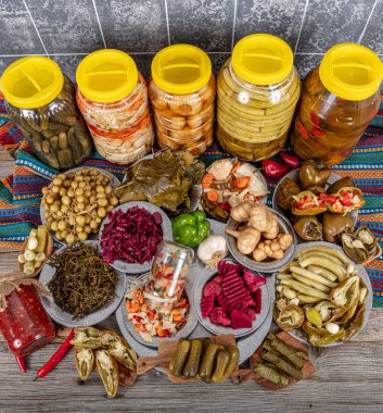 Ev yapımı turşu sergisi. Turşu kavanozu tipleri. Tahta masada farklı türde meyve ve sebze turşusu. Salatalık turşusu, domates, lahana, biber ve sarımsak, salatalık turşusu..