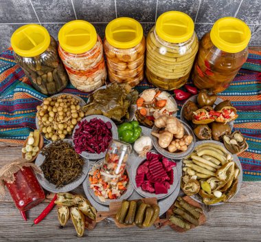 Ev yapımı turşu sergisi. Turşu kavanozu tipleri. Tahta masada farklı türde meyve ve sebze turşusu. Salatalık turşusu, domates, lahana, biber ve sarımsak, salatalık turşusu..