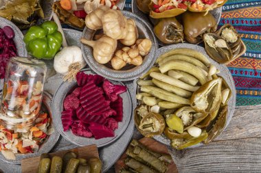 Ev yapımı turşu sergisi. Turşu kavanozu tipleri. Tahta masada farklı türde meyve ve sebze turşusu. Salatalık turşusu, domates, lahana, biber ve sarımsak, salatalık turşusu..