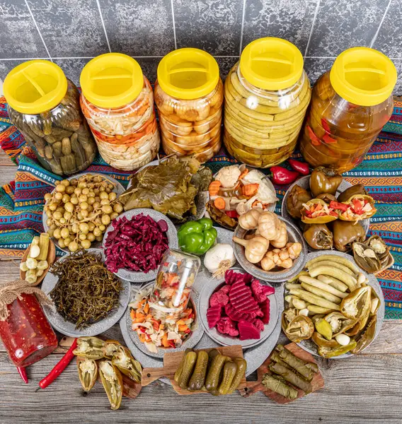 Ev yapımı turşu sergisi. Turşu kavanozu tipleri. Tahta masada farklı türde meyve ve sebze turşusu. Salatalık turşusu, domates, lahana, biber ve sarımsak, salatalık turşusu..