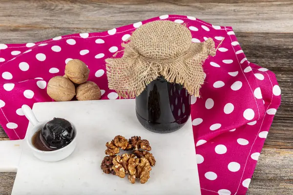 stock image Handmade jam made from green fresh walnuts on a wooden background. Organic walnut jam, healthy food. Young green walnut jam and walnuts in a glass jar on an old wooden table.