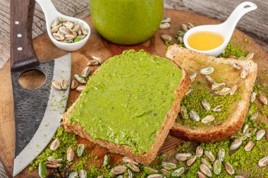 Kavanozda fıstıklı krema ve ahşap masada fındıklar. Cam kavanozda fıstık ezmesi. Ahşap arka planda ev yapımı çiğ organik fıstık ezmesi. Sağlıklı doğal gıda konsepti.