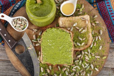 Kavanozda fıstıklı krema ve ahşap masada fındıklar. Cam kavanozda fıstık ezmesi. Ahşap arka planda ev yapımı çiğ organik fıstık ezmesi. Sağlıklı doğal gıda konsepti.