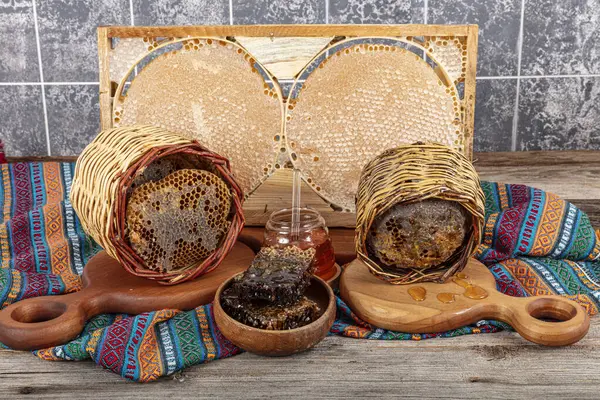 stock image Magical honeycomb close up, Honey harvesting, honey picking. Organic honeycomb (Turkish Karakovan Honey). Organic honeycomb in jar with honey dipper on vintage wooden background.