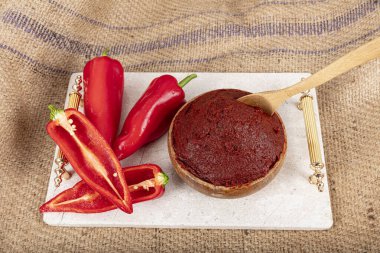 Geleneksel acı biber ezmesi. Türk mutfağı. Bir kase kırmızı biber ezmesi ve domates ezmesi keten masa örtüsünün üzerindeki mermer tepside ekmeğe sürülmüş. Yiyecek konsepti.