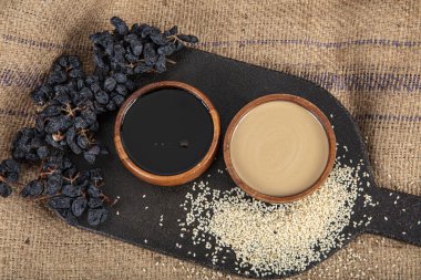 Tahini (susam ezmesi) ve ahşap kasede pekmez. Yerel adı Tahin Pekmez. Kahvaltı için sağlıklı bir seçenek. Türk Pekmez tahin. Sağlıklı yaşam tarzı kavramı.
