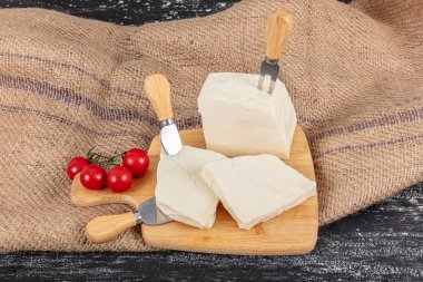 Ezine 'den Feta Cheese. Türk usulü ev yapımı ezin peyniri küpleri ve ahşap ahşap arka planlı ahşap domatesler. Genellikle koyun ve inek sütünden yapılır..