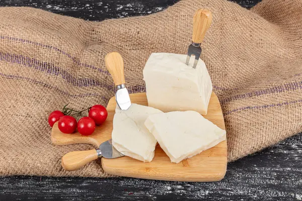 stock image Feta Cheese from Ezine. Turkish style sliced homemade ezine cheese cubes with ceri tomatoes on wooden board with rustic wooden background. it is usually made from sheep and cow milk.