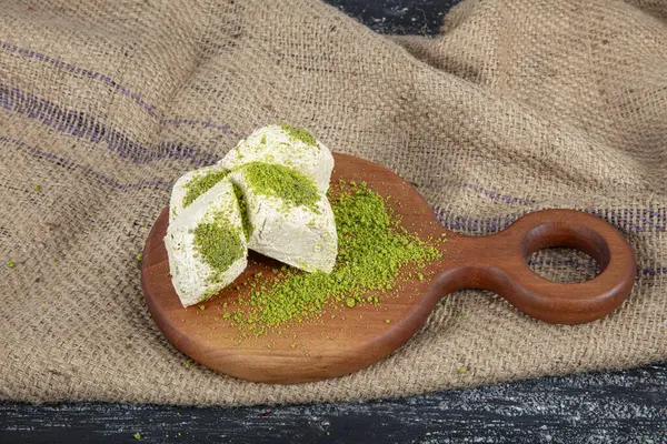 stock image Pistachio halva (Halvah). Halva with pistachios on a rustic wooden table. Close-up of wooden plate with traditional Turkish pistachio halva and slices.