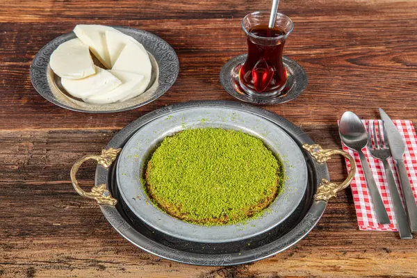 stock image Turkish dessert kunefe, kunafa, kadayif with pistachio powder and cheese, served hot, very sweet. Turkish traditional dessert on wooden background.