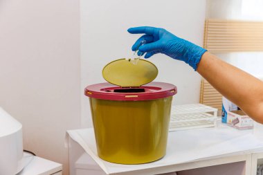 Tıbbi çöp kutusu. Hastanede zehirli atık konteynırı. Tıbbi atıkları ve kullanılmış şırıngaları çöp kutusuna atın. Hemşire kullanılmış şırınga ve şişeyi çöpe attı.. 