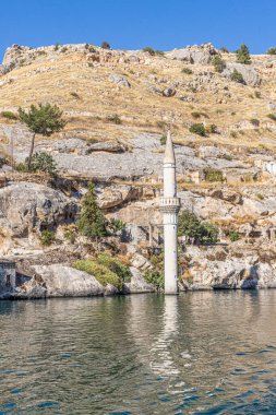 Abandoned old town view in Halfeti Town of Sanliurfa Province. Halfeti village and its submerged minaret and Turkish flags of toursit boats. View of the sunken city Halfeti in Sanliurfa, Turkey. clipart