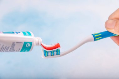 Diş macunu tüpten fırçaya sıkıştı, yakın çekim. Diş macunu diş fırçasına sıkıştırılıyor. Diş bakımı, beyazlatma, fırçalama ve diş sağlığı hizmetleri.