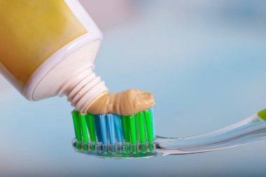 Toothbrush and miswak extract toothpaste. On the toothbrush, squeeze out the toothpaste on a blue background. Applying toothpaste on brush against blurred background. clipart