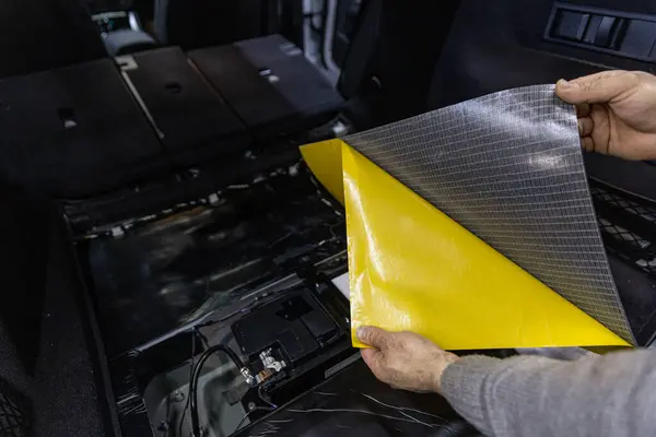 stock image Process of installation of soundproofing material to inside of car. Auto sound insulation.  Audio and vibration isolation. Soft material. Dismantled car. Additional equipment.