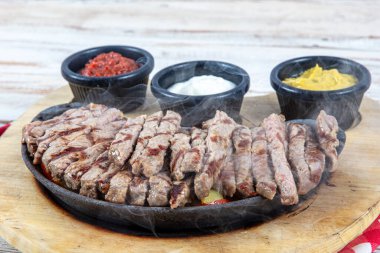 Tavada dolmalık dolmalık biberli sığır eti ve tortilla ekmeği ve sos. Biber, soğan ve ahşap tahtada avokado karışımlı biftek Fajitas..