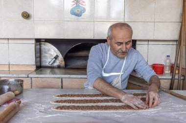 Babadag, Denizli, Türkiye 4 Mart 2024; Baker odun ateşinde kıymalı et pidesi pişiriyor. Hamur, kıyma ve sebzeler Türk pidasının malzemeleridir. Kiymali Pide.