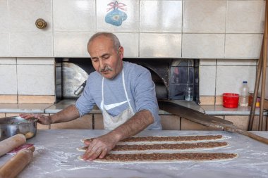 Babadag, Denizli, Türkiye 4 Mart 2024; Baker odun ateşinde kıymalı et pidesi pişiriyor. Hamur, kıyma ve sebzeler Türk pidasının malzemeleridir. Kiymali Pide.