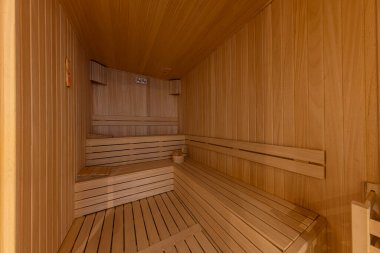 Interior of the Finnish sauna, classic wooden sauna with hot steam. Sauna room at hotel SPA center. Wooden interior baths, wooden benches and sun loungers sauna accessories, spa complex. clipart