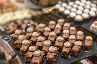 Pasta tezgahları pastalarla dolu bir pastane. Masada bir sürü tatlı, çeşitli hamur işi ürünleri ve çikolatalı çörekler, şeker bağımlılığı. Kahve ve tatlı atıştırmalıklar..