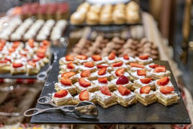 Pasta tezgahları pastalarla dolu bir pastane. Masada bir sürü tatlı, çeşitli hamur işi ürünleri ve çikolatalı çörekler, şeker bağımlılığı. Kahve ve tatlı atıştırmalıklar..