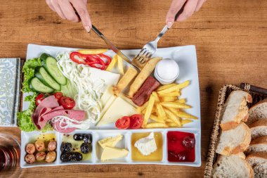 Restoranda kahvaltı hazırlayan bayan, yumurta, ekmek, zeytin ve salatadan oluşan bir Türk kahvaltı tabağı. Tanınmayan kadın lezzetli yemeğinin tadını çıkarırken çatal ve bıçak kullanıyor.