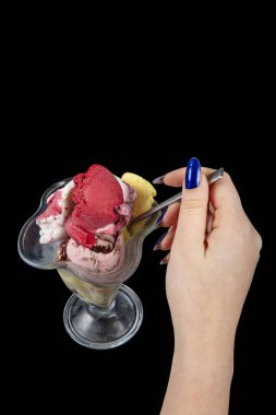 Kaşık ile dondurma yiyen birinin yakın çekimi. Meyveli, tatlı, soğuk dondurma yiyen genç bir bayan. Siyah arkaplanda izole.