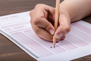 Sınav, optik okuyucuda kalemle sınava giren bir el. Sınav, bir fikir konsepti. Gelecekle ilgili endişe, belirsizlik. Çoktan seçmeli sınav. Yetişkinler sınava giriyor..