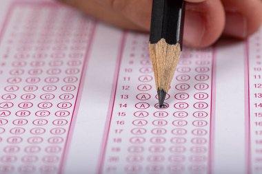 Sınav, optik okuyucuda kalemle sınava giren bir el. Sınav, bir fikir konsepti. Gelecekle ilgili endişe, belirsizlik. Çoktan seçmeli sınav. Yetişkinler sınava giriyor..