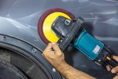 Profesyonel araba temizleyicisi, parlak gri boyanın boya yüzeyini parlatırken hava rastlantısal orbital zımpara makinesi ya da çift aksiyonlu cilalayıcıyı elinde tutar. Araba temizliği, araba yıkama ve boya dolgu maddesi konsepti.