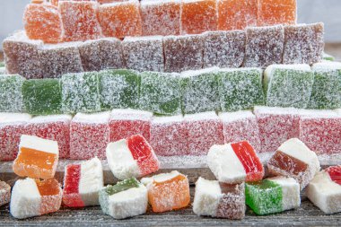 Hindistan cevizi tozuyla kaplanmış, doğal ahşap mermer bir tepside sıralanmış Türk lokum şekerlerinin çeşitli renkleri ve tatları. Kopyalama alanı olan renkli yiyecek arkaplanı.