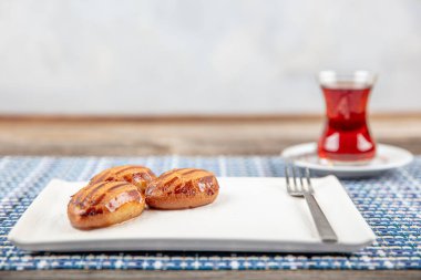 Traditional Turkish Dessert with Tea: Sekerpare. Sekerpare is served with tea on a white plate. clipart