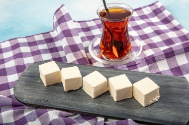 Turkish Traditional Kastamonu Cekme Helva Pismaniye. Halva on a black plate and served with a glass of tea. clipart