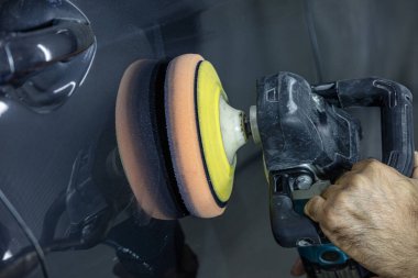 Araba Lehçe balmumu işçisi uygulanan koruyucu bant parlatma önce eller. Polisaj ve parlatma araba. Araba ayrıntılı. Adam elinde bir Parlatıcı tutar ve araba parlatır