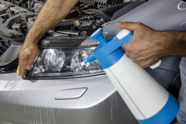 Araba servisinde güç tamponu makinesiyle araba farları temizleniyor. Benzin istasyonunda tampon makinesi olan büyük bir far temizliği. Araba temizleme konsepti. Otomatik temizlik ve cilalama.