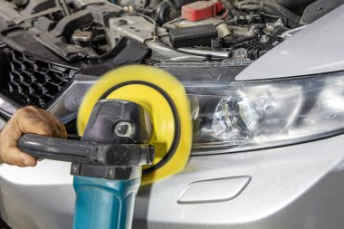 Araba servisinde güç tamponu makinesiyle araba farları temizleniyor. Benzin istasyonunda tampon makinesi olan büyük bir far temizliği. Araba temizleme konsepti. Otomatik temizlik ve cilalama.