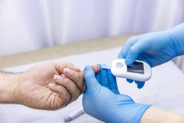 Hastanın kan örneğini parmak batırma kiti ile alan tıbbi çalışanın yakın çekimi. Tıbbi konsept. Diyabet konsepti. Kanında şeker var. Sağlık konsepti. Glikoz ölçer elinde.