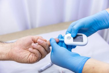 Hastanın kan örneğini parmak batırma kiti ile alan tıbbi çalışanın yakın çekimi. Tıbbi konsept. Diyabet konsepti. Kanında şeker var. Sağlık konsepti. Glikoz ölçer elinde.