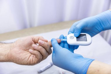 Hastanın kan örneğini parmak batırma kiti ile alan tıbbi çalışanın yakın çekimi. Tıbbi konsept. Diyabet konsepti. Kanında şeker var. Sağlık konsepti. Glikoz ölçer elinde.