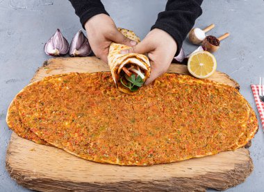 Geleneksel Türk lahmacunu tutan adamın eli. Hindi ünlü fast food lahmacun yenmek için paketlenmiş. Türk Gıda: lahmacun ahşap bir masaya yakın plan.