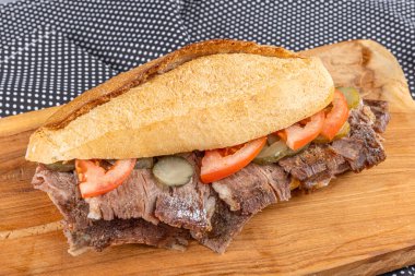 Tahta bir tabakta ekmek arasında et donörü. Geleneksel Türk mutfağı bağışçısı. Ekmek arasında et donörü. Turşu ve domatesle servis edilir. (Türkçe adı: ekmek ve Türk kebabı arasında et donörü).