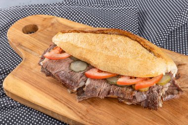 Tahta bir tabakta ekmek arasında et donörü. Geleneksel Türk mutfağı bağışçısı. Ekmek arasında et donörü. Turşu ve domatesle servis edilir. (Türkçe adı: ekmek ve Türk kebabı arasında et donörü).