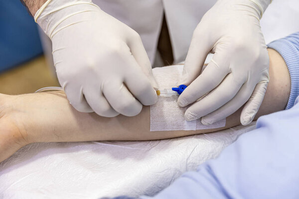 Врач вставляет иглу в вену пациента. Сестра соединяет капельницу. Медсестра готовит и регулирует вливание для пациента в больнице. Концепция здравоохранения.