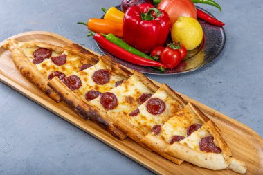 Biberli ve peynirli Türk pide tabağı. Geleneksel Türk pidesi. (pepperonili pide) ahşap serviste. Türkçe adı: Sucuklu pide.